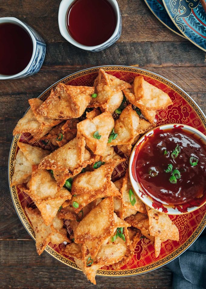 crab rangoon with sweet and sour dipping sauce on a red plate