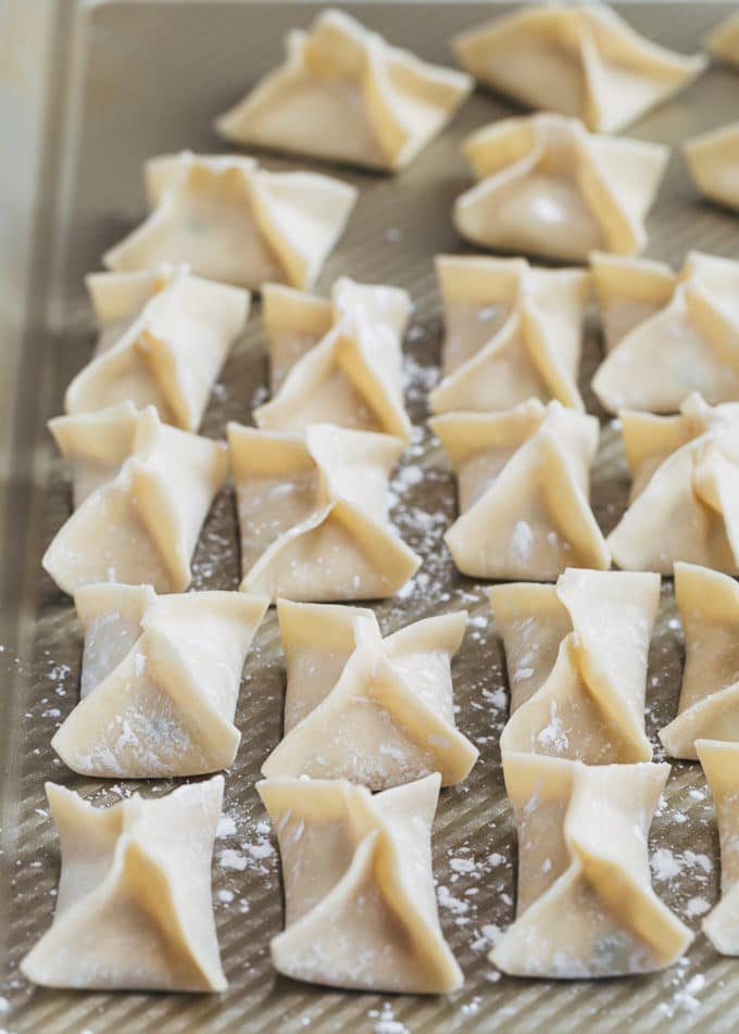 folded crab rangoon wontons on a baking sheet