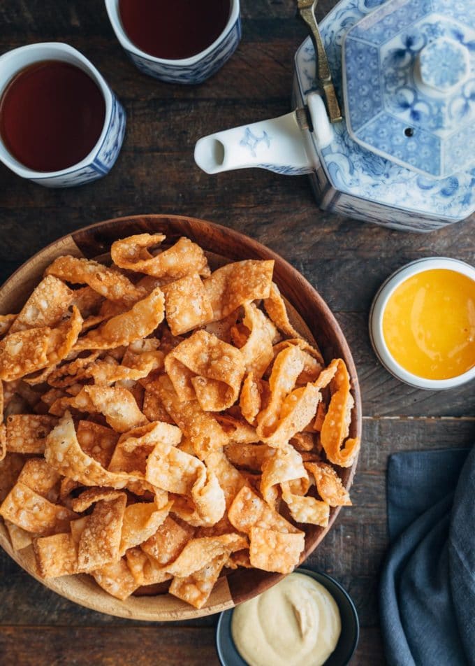 overhead view of crispy wonton strips with dipping sauces and cups of tea