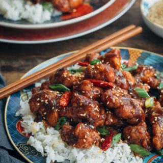 General Tso's Chicken over jasmine rice on a plate with chopsticks