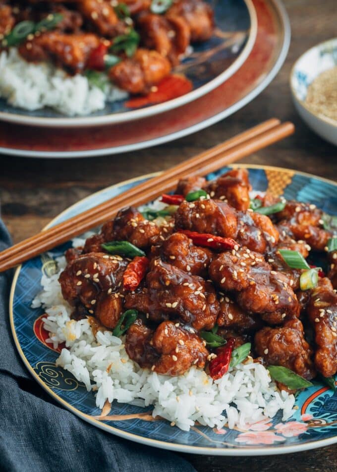General Tso's Chicken over jasmine rice on a plate with chopsticks