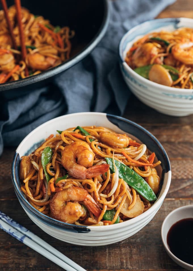 shrimp lo mein served in bowls with soy sauce on the side