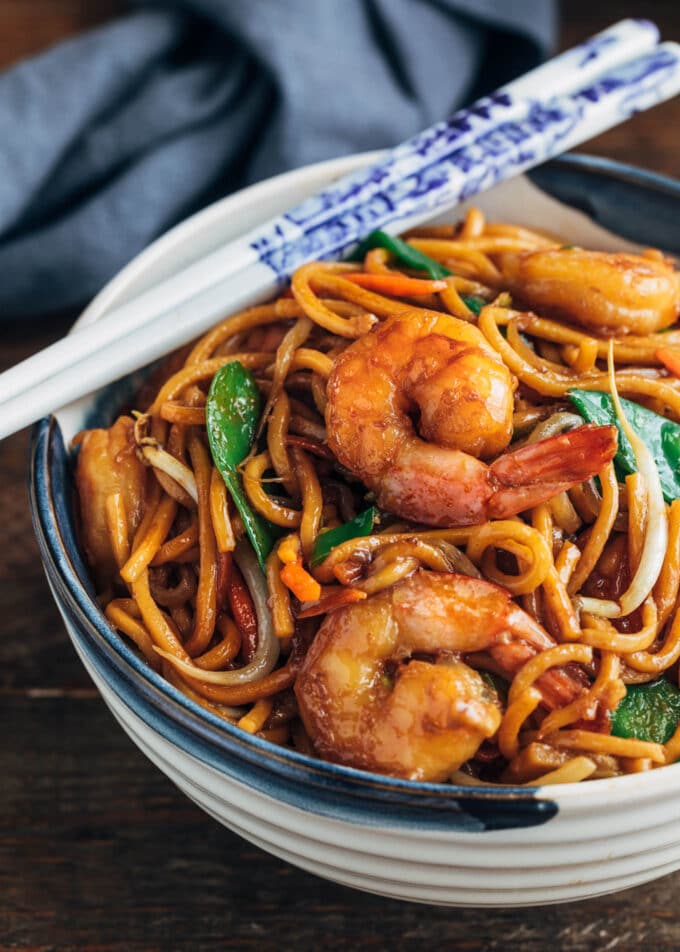 shrimp lo mein in a ceramic bowl with white chopsticks