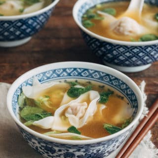 Sopa wonton en cuencos azules con estampado floral y palillos de madera