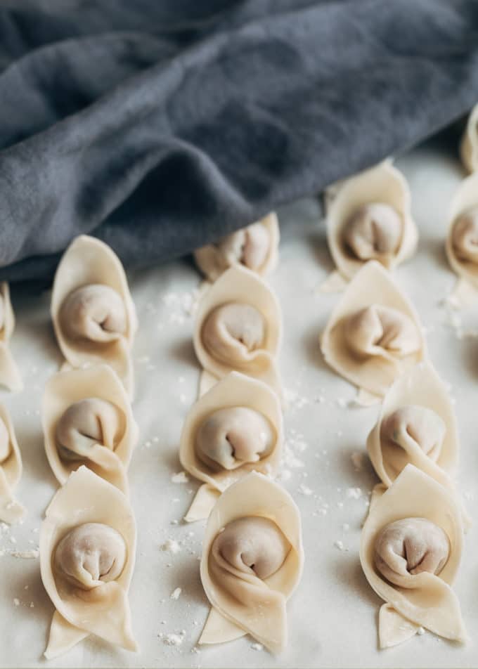 folded wontons on a perchment lined baking sheet