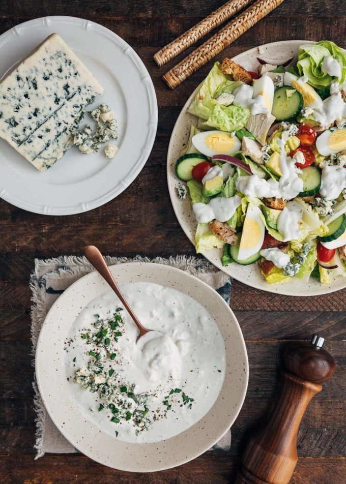 homemade blue cheese dressing in a bowl next to a house salad