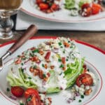 classic wedge salad with iceberg lettuce, bacon, and blue cheese dressing on a plate