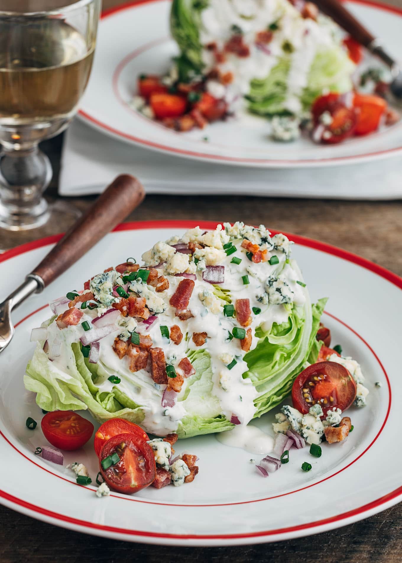 classic wedge salad with iceberg lettuce, bacon, and blue cheese dressing on a plate