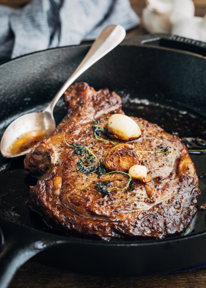 pan seared steak in a cast iron pan with garlic and butter