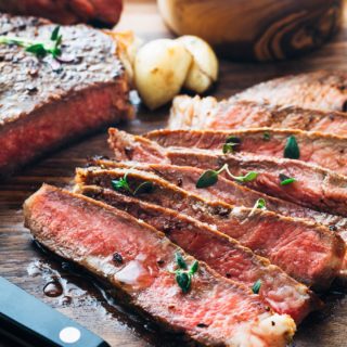 slices of pan seared ribeye steak on a cutting board