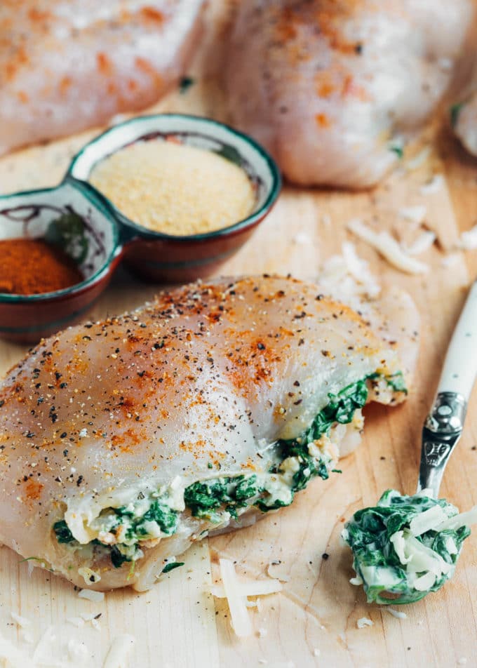 raw spinach stuffed chicken breast on a wood board