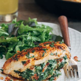 spinach stuffed chicken breast on an ivory plate with salad greens