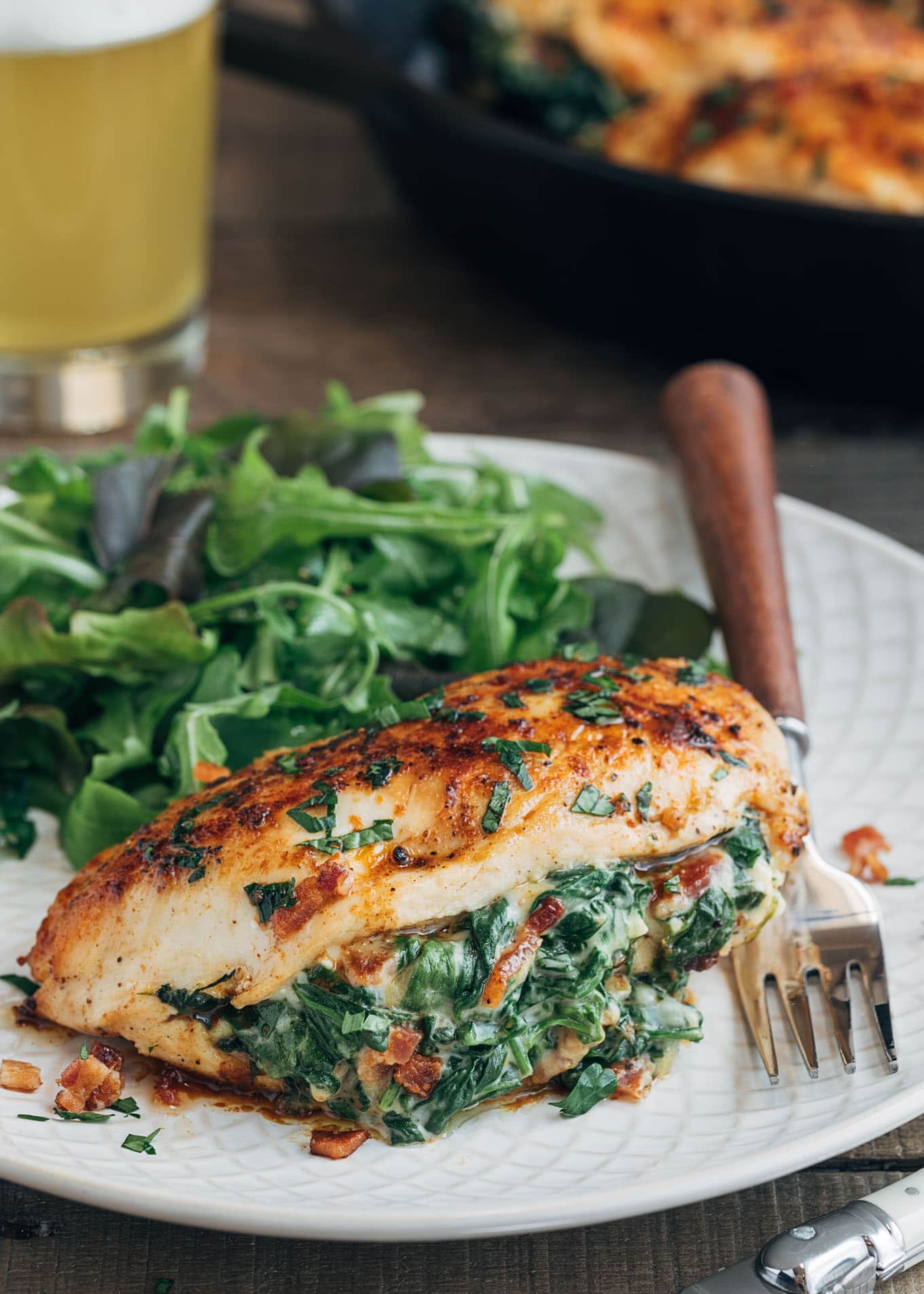 spinach stuffed chicken breast on an ivory plate with salad greens