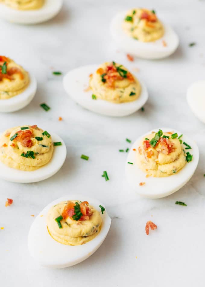 filled deviled eggs with bacon and horseradish on a white marble board