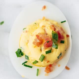 bacon deviled egg with horseradish and chives on a marble board