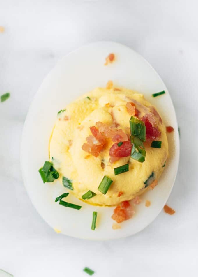 bacon deviled egg with horseradish and chives on a marble board