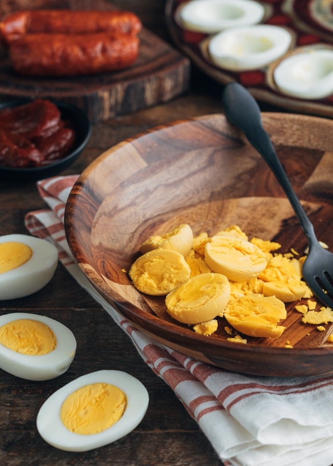 hard boiled egg yolks in a wooden bowl and halved hard cooked eggs