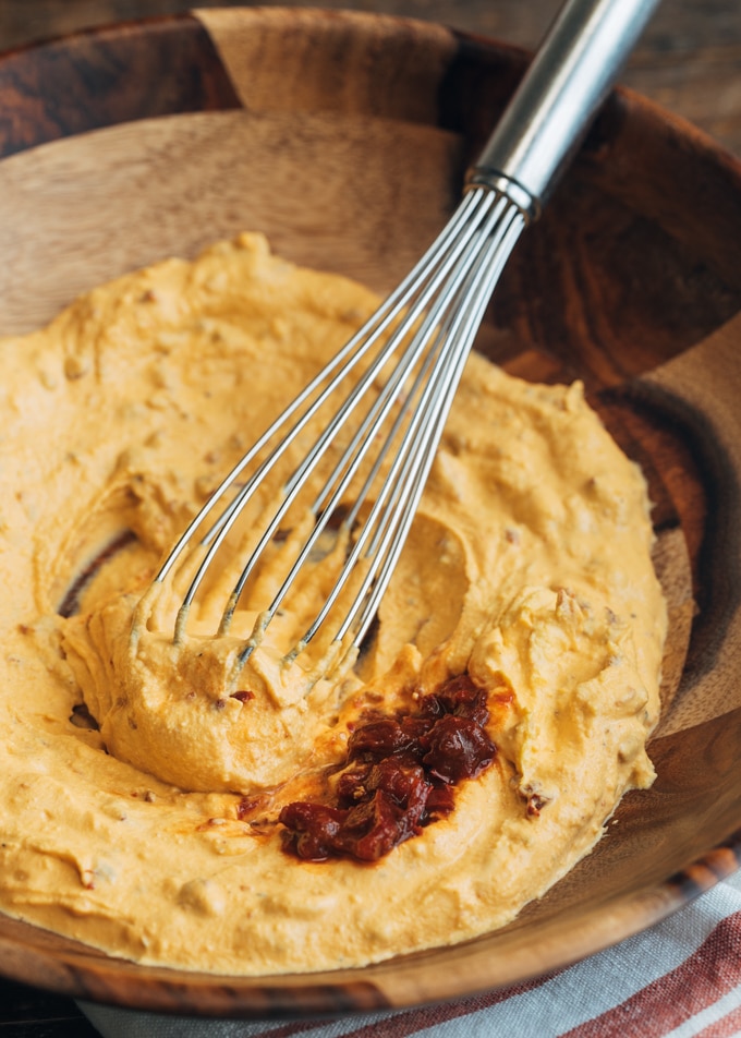 filling for chipotle deviled eggs in a wooden bowl with a whisk