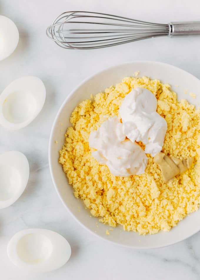 hard boiled egg yolks in a bowl with mayonnaise, sour cream, and Dijon mustard