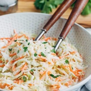 homemade coleslaw in a bowl with wooden serving spoons