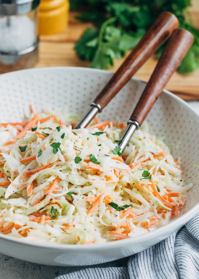 homemade coleslaw in a bowl with wooden serving spoons
