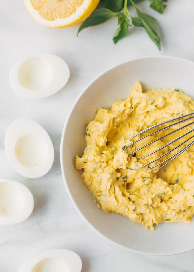 Italian deviled egg filling in a bowl with a whisk