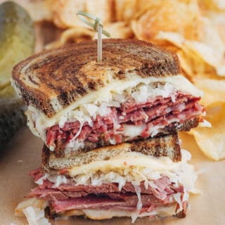 stacked halves of a grilled reuben sandwich with potato chips