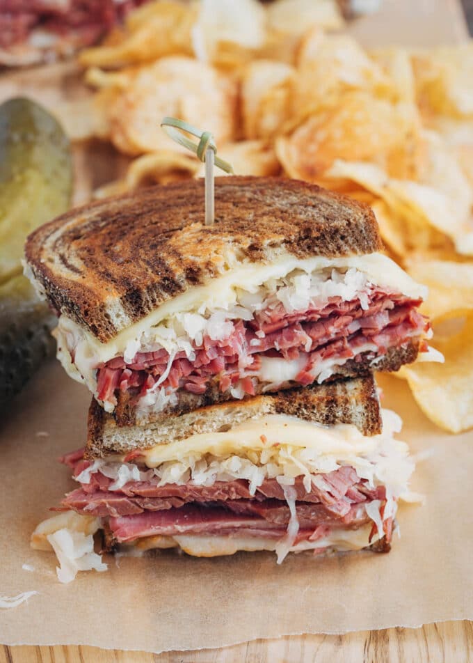 stacked halves of a grilled reuben sandwich with potato chips