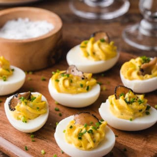 truffled deviled eggs with chives on a wood board