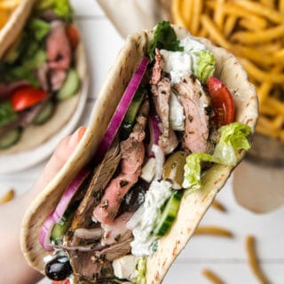 closeup of a hand holding a roasted lamb pita