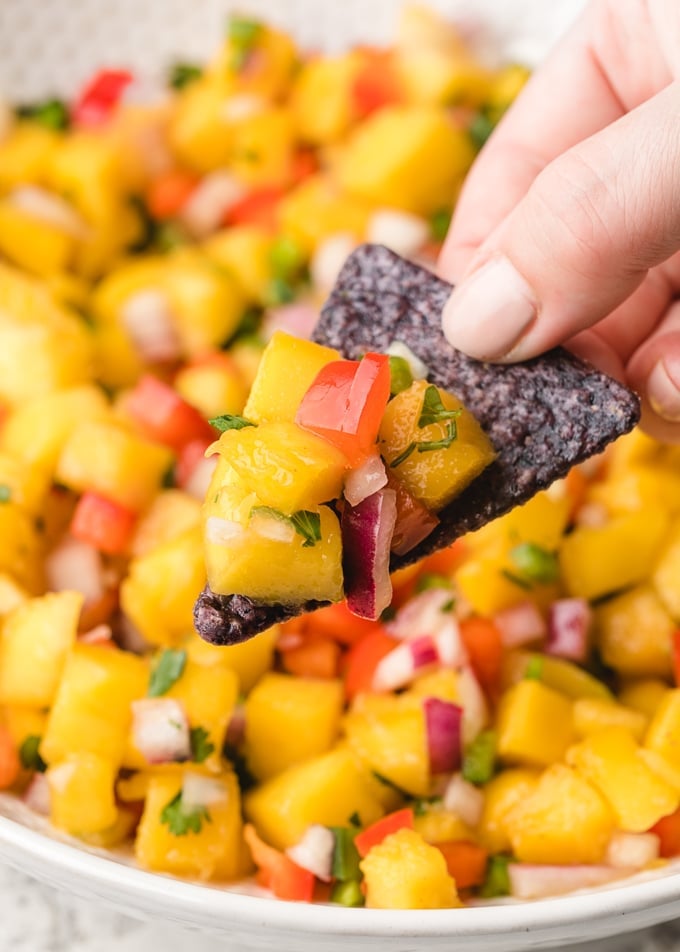 mango salsa scooped onto a blue corn chip