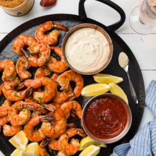 roasted shrimp cocktail with two dipping sauces on a black handled platter