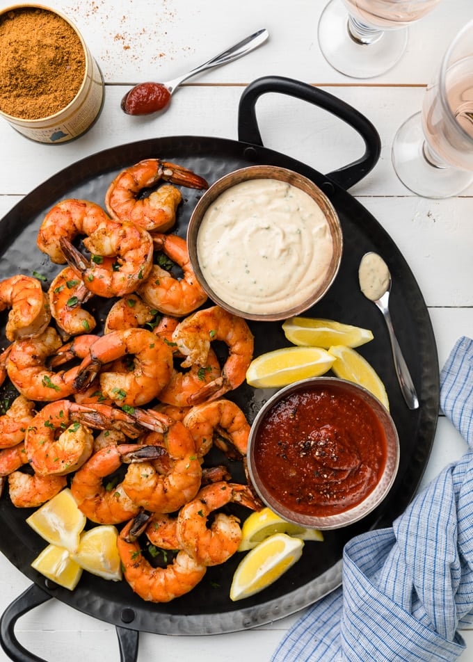 {sponsored} roasted shrimp cocktail with two dipping sauces on a black handled platter