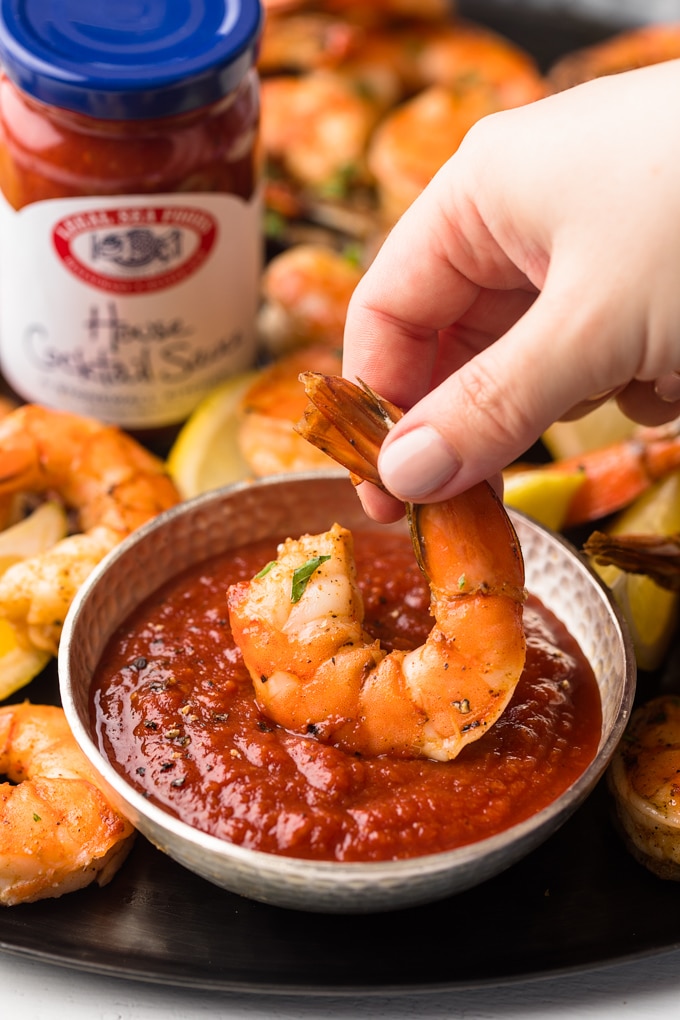 {sponsored} roasted colossal shrimp dipped into a bowl of bloody mary cocktail sauce 