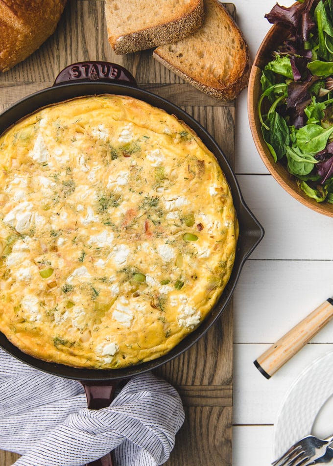 overhead of goat cheese and salmon frittata with slices of toast and a salad
