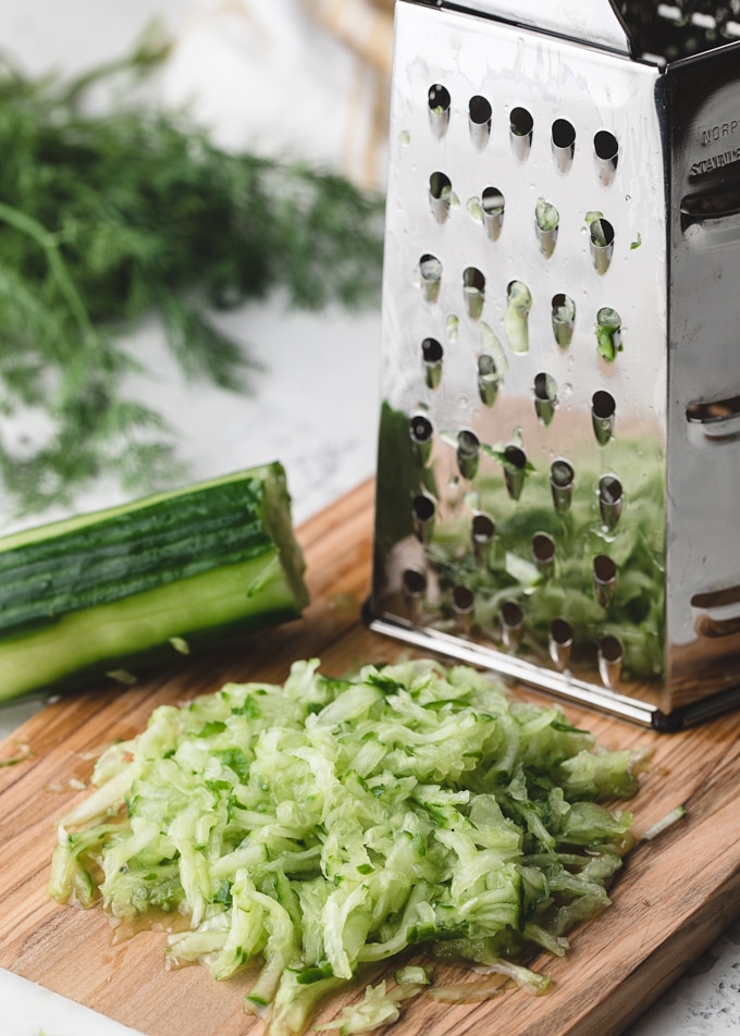 shredded cucumber on a cutting board with a box grater