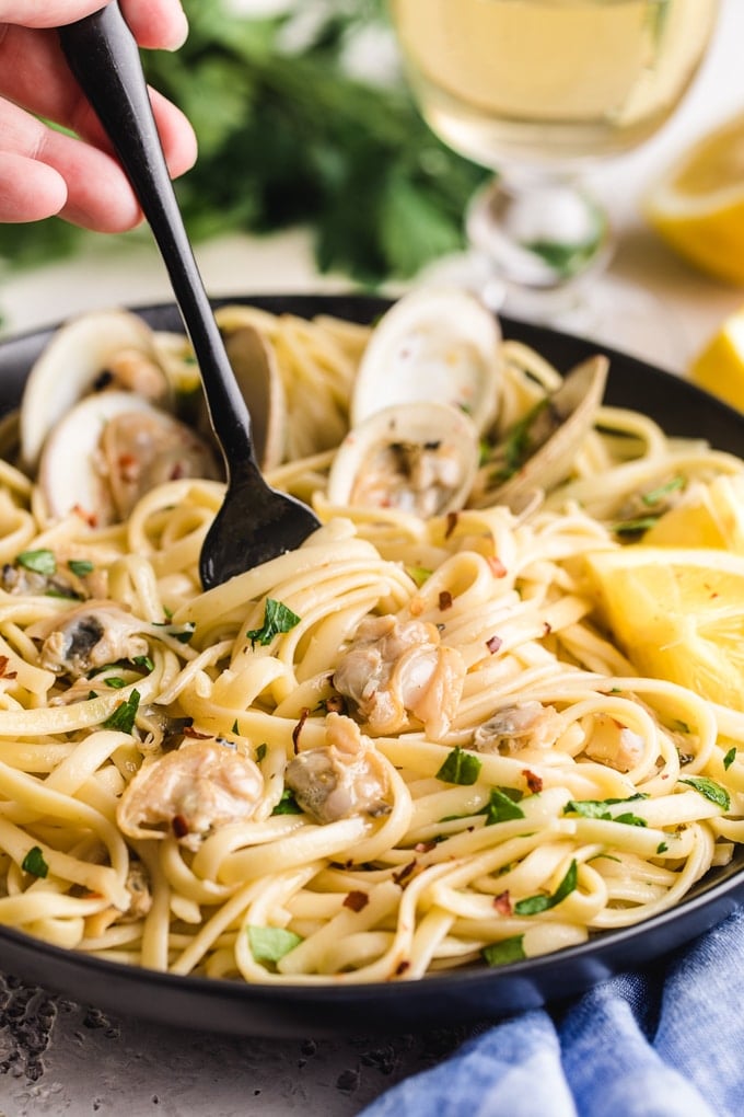 bowl of linguine with clams with a fork twirling pasta