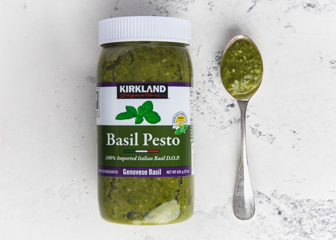 jar of kirkland basil pesto next to a spoonful of pesto