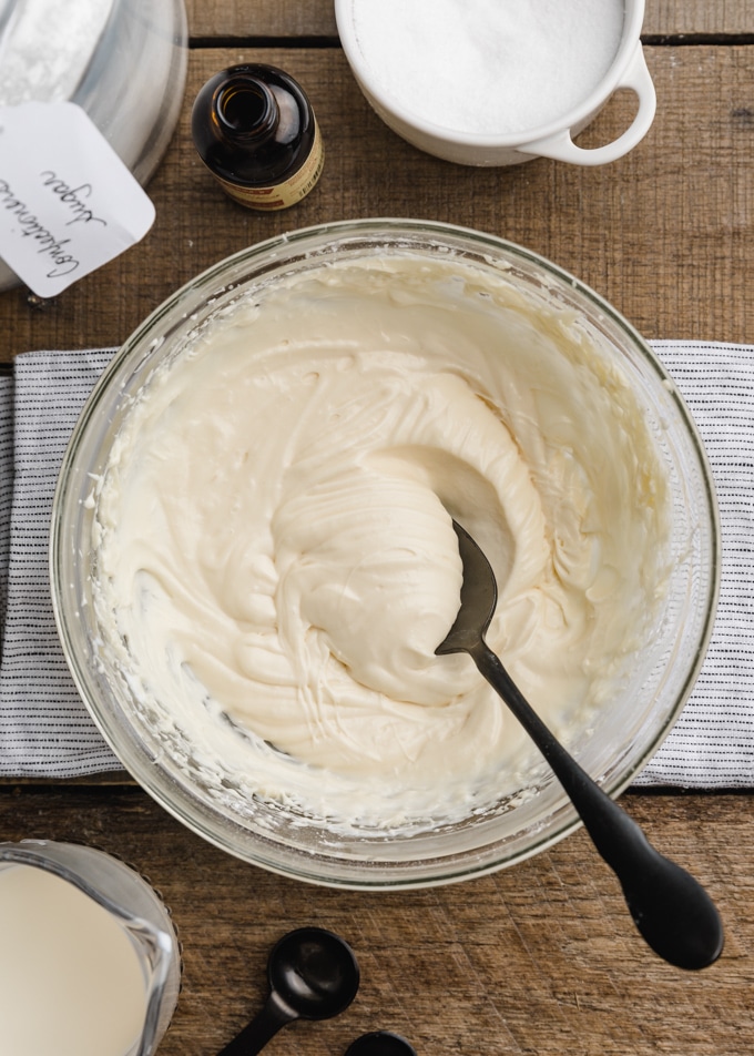 overhead photo of cream cheese glaze in a bowl with a black spoon