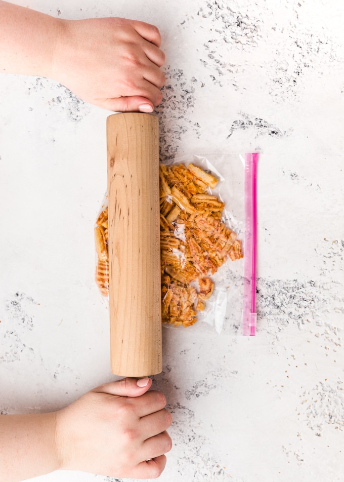 cheese crisps in a plastic bag being crushed with a rolling pin