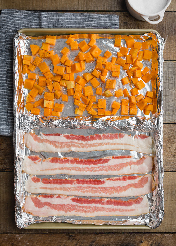 butternut squash cubes and bacon on a foil lined baking sheet