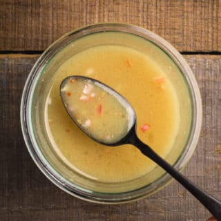 maple dijon vinaigrette on a black spoon over a glass jar