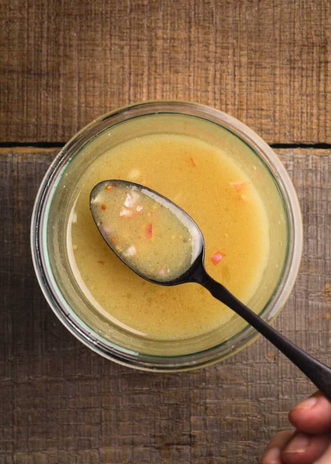 maple dijon vinaigrette on a black spoon over a glass jar