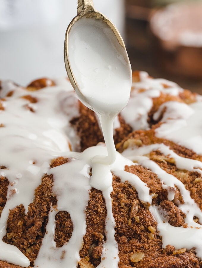 closeup of powdered sugar glaze being drizzled onto a coffee cake from a gold spoon