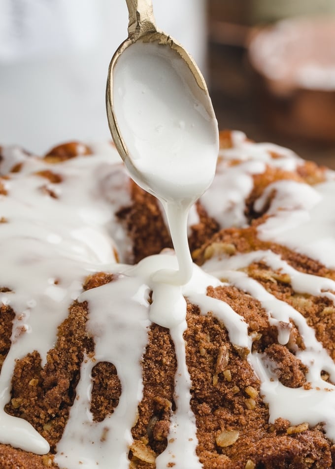 closeup of powdered sugar glaze being drizzled onto a coffee cake from a gold spoon