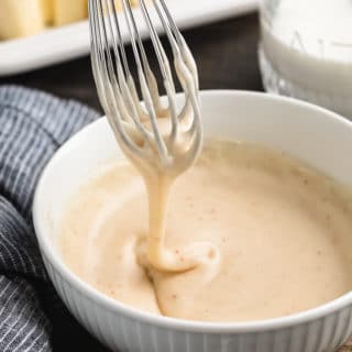 brown butter glaze dripping from a whisk into a white porcelain bowl