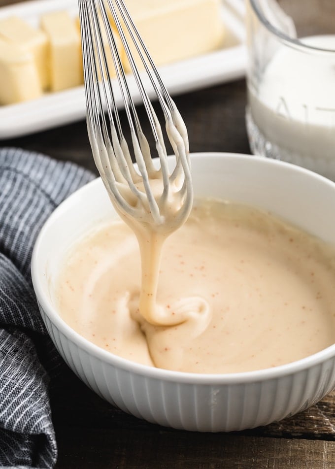 brown butter glaze dripping from a whisk into a white porcelain bowl