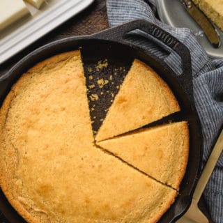 overhead of buttermilk cornbread sliced into wedges in a cast iron skillet