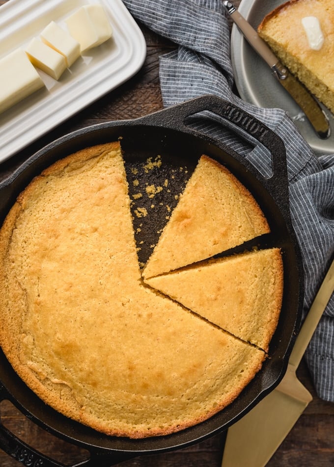 overhead of buttermilk cornbread sliced into wedges in a cast iron skillet