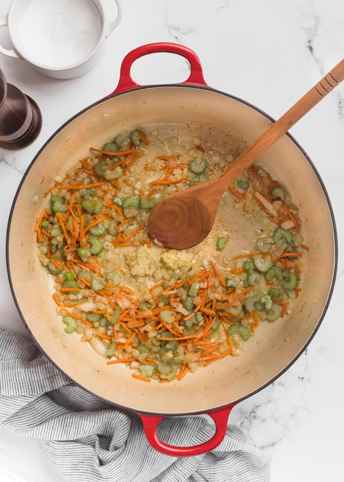 sauteed mirepoix in a Dutch oven with a wooden spoon on a marble board